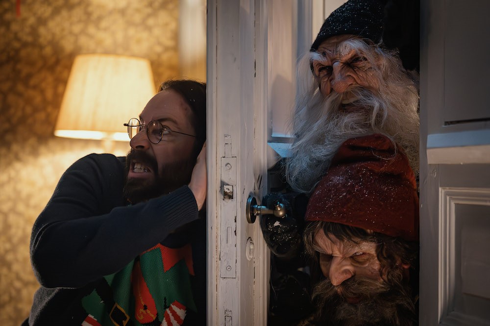 Two creatures trying to get into the house, one man holds the door, trying to keep them out.
