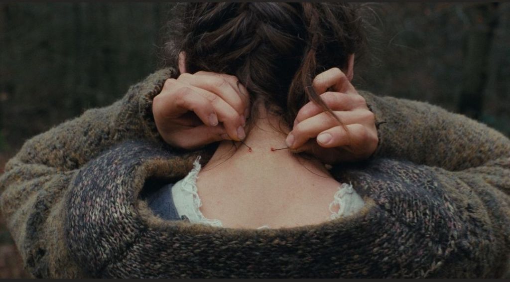 A woman putting her necklace on viewed from behind