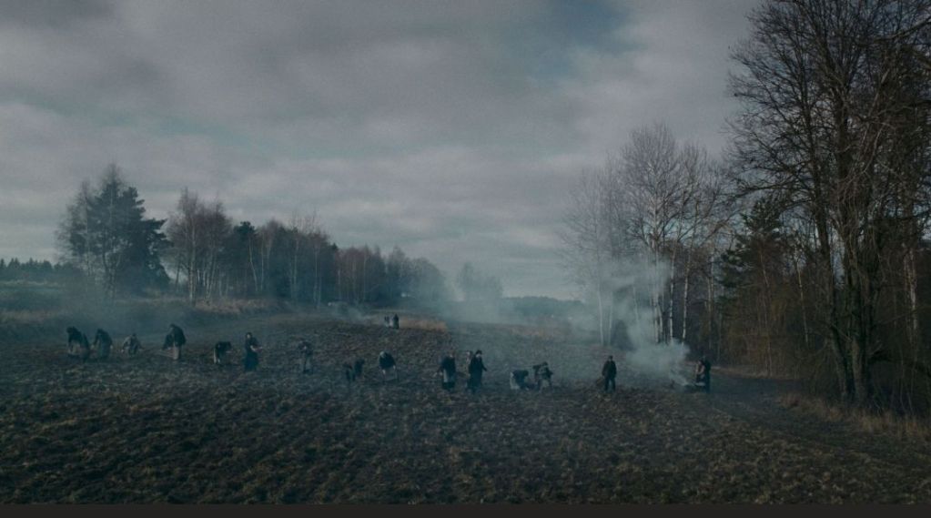 A filed with workers in it and light fog