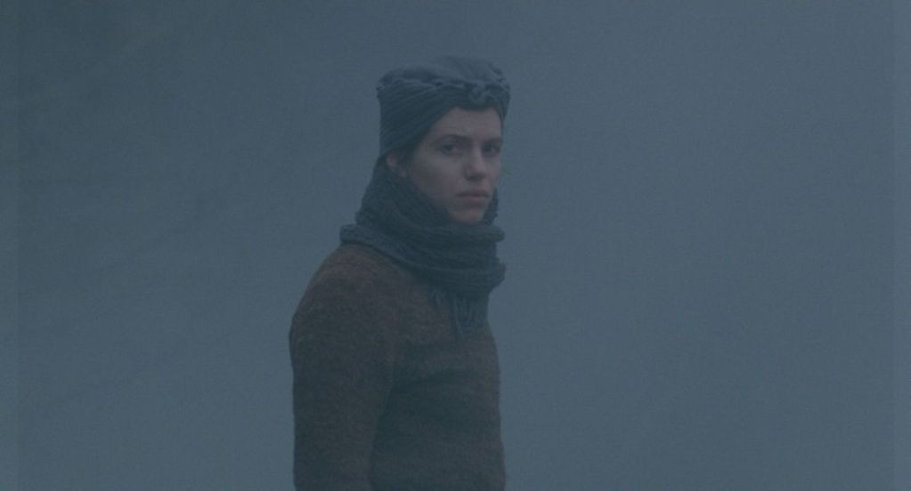 Woman standing looking back through fog
