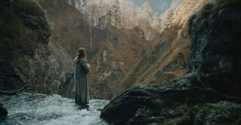 Man standing in shallow creek look at the surrounding cliff face