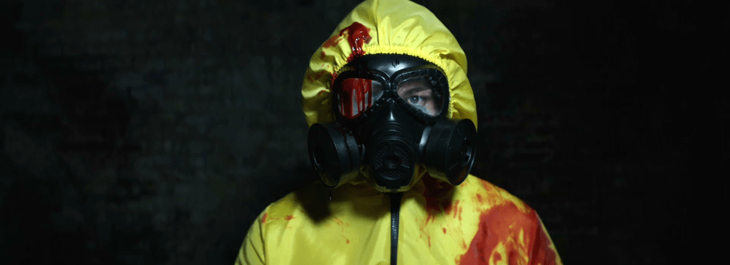 man in yellow hazmat suit, covered in blood
